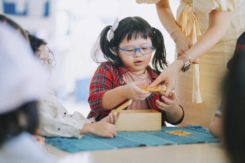 A woman is helping a child at a table.